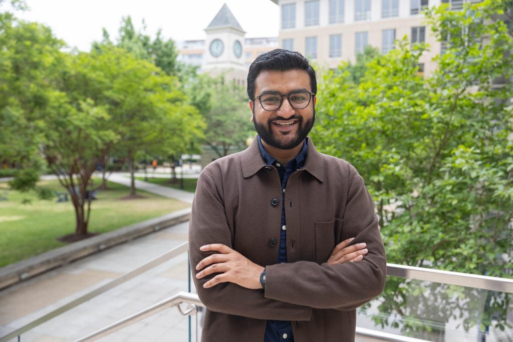 Portrait of a man standing and smiling on campus