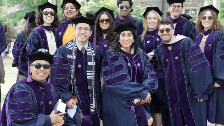 A group of smiling graduates in regalia.