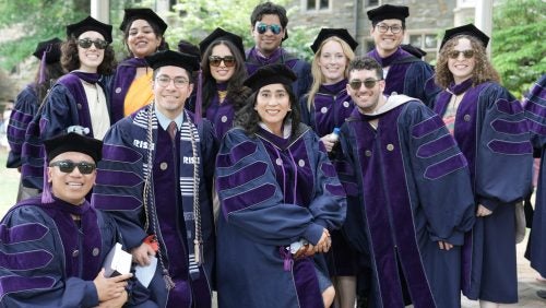 A group of smiling graduates in regalia.