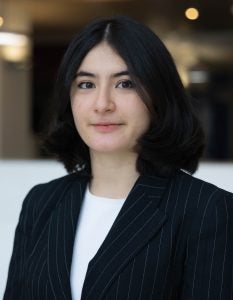 Headshot of Agavni, wearing a black jacket, white shirt, and smiling