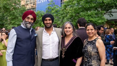 Four adults in cocktail attire pose for a photo on the Law Center campus.