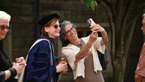 A loved one takes a selfie with a graduate in regalia.