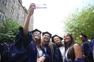 Four graduates smile for a selfie.