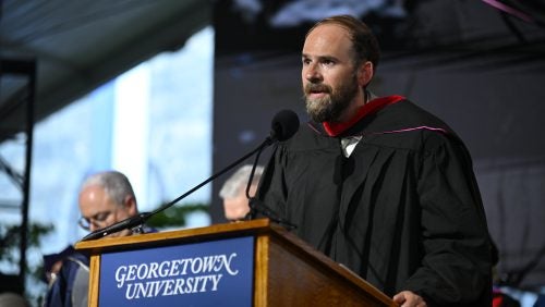 A man in regalia standing and speaking at a podium.