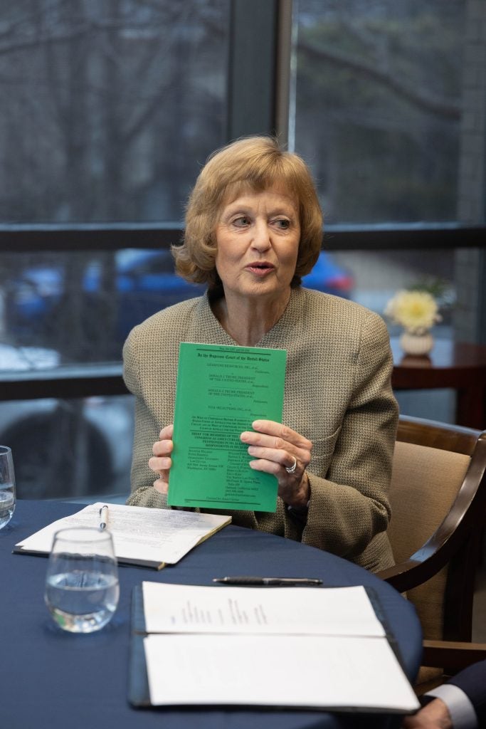 A woman holding up a document with a green cover