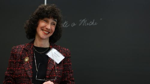 A woman standing in front of a blackboard, smiling