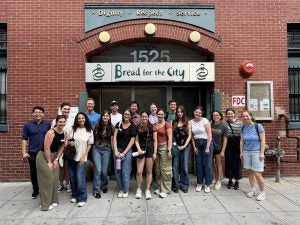A group of students on the sidewalk in front of the entrance to Bread for the City.