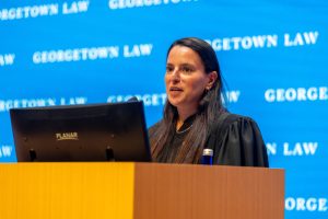A woman with dark hair wearing judges robes stands at a podium