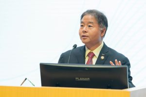 A man wearing a suit stands and speaks at a podium