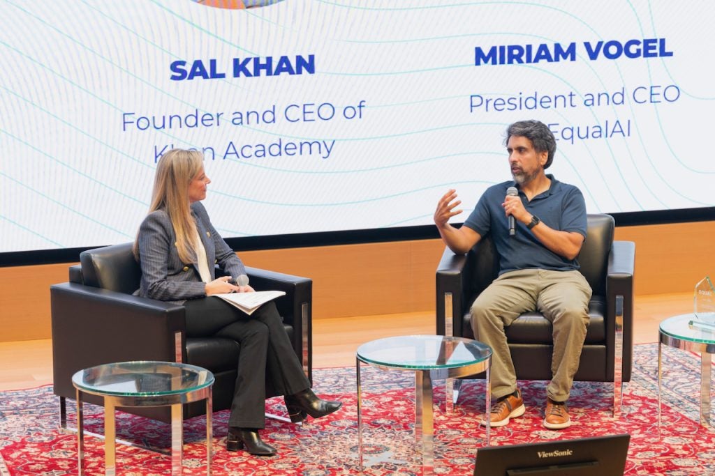 Two people sit onstage and engage in conversation