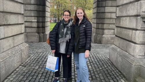 two students in casual wear smiling outside 