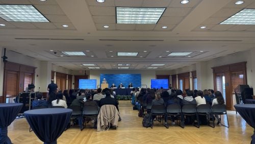 A speaker panel with 100 guests sitting and reception tables