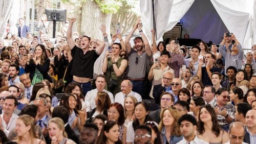 Attendees in the back of the crowd cheer on graduates at Commencement 2025.
